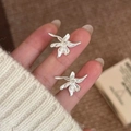 Silver flower stud earrings with metallic luster finish shown on a soft background - Silver (Silver Earring Post)
