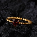 Nahaufnahme eines herzförmigen roten Edelsteinrings mit gedrehtem Goldband auf Fels - Natürlicher Granat Gold