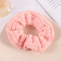 Detail of pink knitted scrunchie texture on a desktop with elegant lifestyle props - Pink