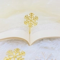 Marcapáginas de copo de nieve en metal dorado y plateado dentro de un libro abierto - Dorado