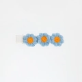 Detail shot of three blue embroidered flowers with orange centers on a fabric hair clip - Blue and Orange