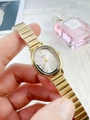 Close-up of a gold oval watch with a silver dial and metallic chain strap worn on wrist - Gold Band White Dial