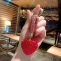 Macro shot of red clay heart keychain with full rhinestones and golden metal ring - Red