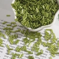 Perle di vetro verde oliva foderate d'argento sparse su pagine di libri vintage - verde oliva