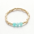 Detailed shot of handmade beaded ring with gold spheres and turquoise crystal accents - Gold Blue