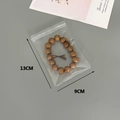 Detailed view of 13x9cm thickened PVC self-sealing bag with wooden bead bracelet - 30 Silk 9x13cm