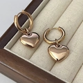Détail des boucles d'oreilles à pendentif cœur en or rose dans un coffret à bijoux en bois - Tout Or Rose