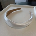 Primer plano de diadema de satén blanco con textura sedosa en una bandeja de purpurina - Blanco