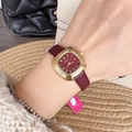 Elegant women's watch with red dial, gold case, and dark red leather strap on wrist - Threaded Bezel Style