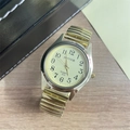 Detail of quartz watch with stretch band and clear Arabic numerals on a wooden surface - Men's Watch / Gold Steel Strap Gold Dial