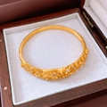 Detailed close-up of a golden floral embossed bangle with sparkling stone accents in a gift box - Bracelet-Gold