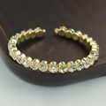 Macro detail of gold-plated bangle featuring claw-set round cubic zirconia stones - Gold