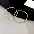 Irregular textured gold hoop earrings displayed on black silk and grey background - Wave Irregular Large Hoop / Gold