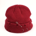 Close-up of distressed knit beanie with silver rings and safety pin in burgundy red - Red