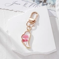 Detailed close-up of handmade pink dried flower resin heart charm with gold lobster clasp - Pink Flower Wing