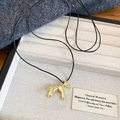 Detailed view of a golden pony pendant necklace with black cord on a velvet jewelry tray - Gold Enamel Horse Pendant with Black Cord