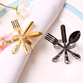 Close-up of golden and silver cutlery-shaped metal napkin rings on a white napkin - Iron Ring