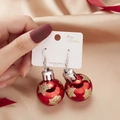 Detail of red Christmas bulb earrings with gold glitter stars on champagne velvet - Red Gold Star Style
