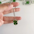 Macro shot of a clear sphere keychain featuring a real green four-leaf clover specimen inside - Round Ball Clover / Keychain