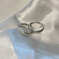 Close-up of polished silver hoop earrings on a white silk fabric background - Smooth Hoop / Silver