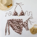 Detailed flat lay of a 3-piece floral bikini set with a sarong and golden pendant - Coffee