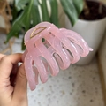 Close-up of a pink translucent large hair claw clip with golden metal spring details - Jelly Pink