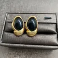 Vintage style gold-plated stud earrings with oval black gemstones on a jewelry box - Black