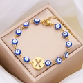 Golden evil eye chain bracelet featuring a circular gold pendant with letter X cutout - Letter X