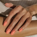Glossy warm orange square press-on nails shown on hand against beige knit background - Warm Orange (CW428)