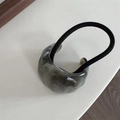 Detail of translucent grey-green resin ring with black elastic hair tie on a desk - Grey Marble