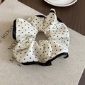 Polka dot silk fabric scrunchie with black trim on a textured book surface - White Scrunchie