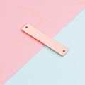 Primer plano de un conector rectangular de oro rosa sobre fondo rosa y azul pastel - Doble Agujero / 6x32mm / Oro rosa