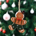 Macro view of gingerbread man ornament with green overalls and snowy Christmas tree background - Suspender Style