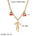 Gold cherry necklace with bow pendant, green leaves and red charms on white background - Bowknot Cherry Style (TN3600)