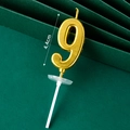 Golden number 9 birthday candle with white base standing 4.4cm tall on green background - Golden Long Number Candle 9
