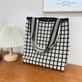 Macro detail of black and white checkered knit tote bag on wooden desk with lamp - 11 3D Grid Black Beige