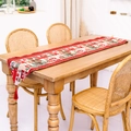 Christmas knit table runner with red tassels and reindeer patterns on a wooden table - Candle