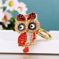 Detail of a sparkling gold owl keychain with red enamel and clear crystal rhinestones - Bow Owl Red