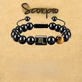Adjustable Scorpio bracelet with tiger eye stone and black beads on parchment background - Scorpio