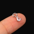 Silver teardrop zircon charm with three-prong setting shown on fingertip for size - CC164 Teardrop / White Gold