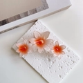 Detail of large floral claw clip with orange-pink gradient resin flowers and sturdy grip - Orange
