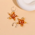 Macro detail of amber glass starfish pendants with white polka dots and clear hooks - Brown