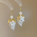 Pendientes de hoja dorada y racimo de perlas estilo francés en fondo beige cálido - Gancho de oreja - Dorado