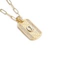 Détail macro du pendentif plaque dorée avec texture tissée, pierres et lettre O en argent - Lettre O