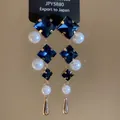 Dettaglio di orecchini lunghi pendenti con cristalli blu profondo e perle bianche eleganti - Perno S925 Oro Blu Scuro