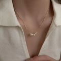 Detailed close-up of a gold-plated pearl pendant necklace worn on a woman's collarbone - Pearl Chain Style