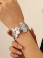Dettaglio di un bracciale a fiori argentato con texture rugosa sul polso - Bracciale Rigido a Fiore Argento (WG-1148)