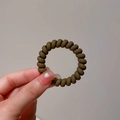 Detail eines dunkelbraunen Spiral-Haargummis für Damen aus elastischem Material - Dunkelbraunes Telefonkabel Haargummi