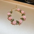 Close-up of golden bracelet featuring pink 3D roses, green leaves, and pink pearls - Pink Rose Bracelet