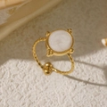 Hammered gold oval ring with white glitter inlay on a textured minimalist background - White